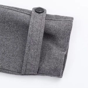 Détail du poignet d'un manteau en laine gris avec bouton et sangle décorative