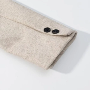 Detailed close-up of light gray wool coat sleeve featuring two black decorative buttons