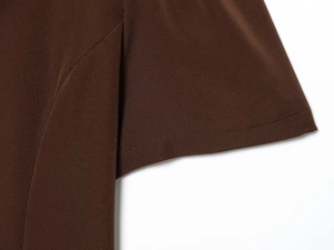Gros plan détaillé des coutures et du tissu tissé marron chocolat sur une robe courte plissée