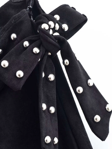 Detailed macro shot of a black suede waist bow featuring silver metal rivet studs