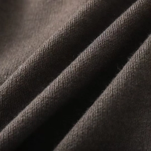 Gros plan sur un tricot marron foncé doux avec une texture fine et un drapé naturel