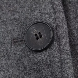 Vue macro d'un manteau en laine gris foncé montrant un bouton noir et le tissu épais