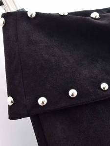 Close-up of matte black suede trousers with decorative silver studs and folded design