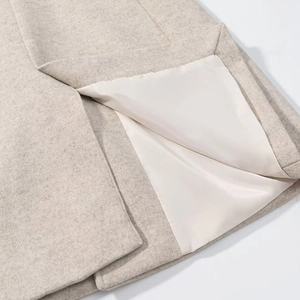 Close-up detail of beige wool coat hem showing high-quality stitching and satin lining