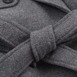 Gros plan d'un manteau en laine gris avec taille ceinturée texturée et tissage détaillé