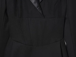 Detailed view of the V-neck with satin lapels and slimming corset stitching on black dress