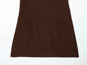 Détail d'une robe marron foncé avec deux poches passepoilées symétriques et tissu texturé