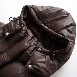 Detail einer dunkelbraunen Glanz-Pufferjacke mit Kapuze, Ausschnitt und Metalldruckknöpfen