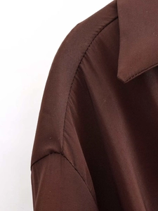 Vue détaillée de la couture et de la texture fine du tissu sur une chemise marron foncé