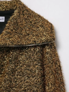 Détail d'un blouson aviateur doré avec texture effilochée et fermeture éclair métallique