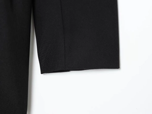 Detailed close-up of smooth black fabric and neat stitching on dress sleeve cuff