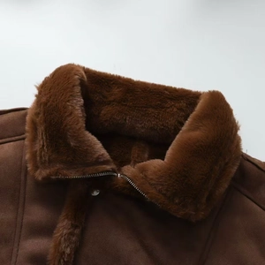 Detail shot of brown faux suede jacket featuring thick plush fur collar and metal zipper