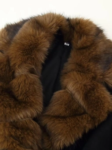Detail of dark brown faux fur collar on black wool coat with soft texture and refined stitching