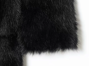 Gros plan sur la texture épaisse en fausse fourrure noire de la manche du manteau