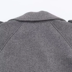 Détail du manteau en laine gris montrant la double couture et la texture du tissu