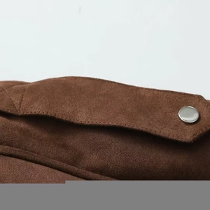 Detail shot of a brown suede jacket collar with a metallic button and stitching