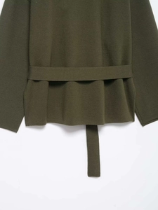 Detail of olive green knit sweater featuring a matching waist belt and textured fabric