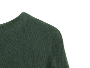 Close-up of deep green knit fabric showing fine texture and seamless stitching details