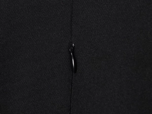 Detail shot of the hidden zipper on a black V-neck dress with smooth fabric texture