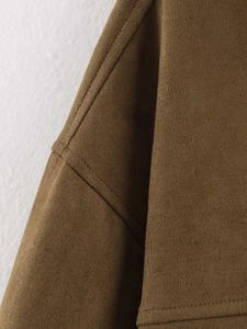 Close-up of deep brown faux suede fabric texture and detailed stitching on the jacket