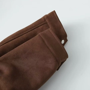 Detailed close-up of dark brown suede jacket cuff with double stitching and white snap button