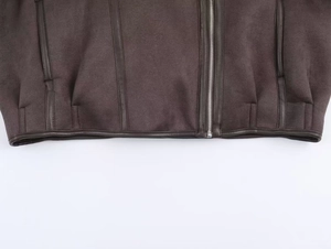 Dettaglio dell'orlo della giacca in scamosciato con piping in pelle marrone e zip in metallo