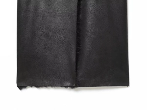 Gros plan d'un manteau en peau retournée noire avec cuir gaufré et doublure en peluche