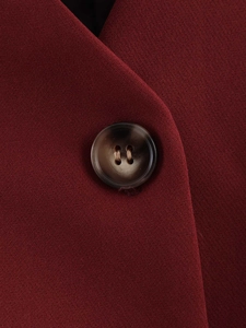 Detail of a dark wine red vest showing the fine fabric texture and tortoiseshell button
