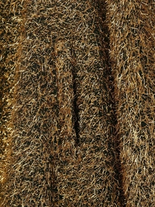Détail macro de la veste bomber avec franges métalliques dorées sur fond noir