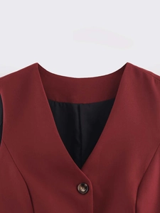Detail view of burgundy V-neck vest featuring a smooth woven texture and tortoise button