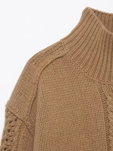 Detail of camel chunky knit sweater featuring cable patterns and ribbed half-high collar
