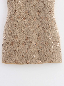 Close-up of gold sequined tweed fabric detail showing premium texture and fringe trim