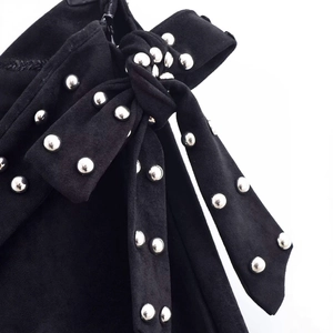 Elegant high-waist wide-leg pants in black suede featuring silver studs and bow detail