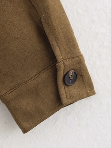 Close-up of suede jacket sleeve cuff featuring textured marble-patterned brown button