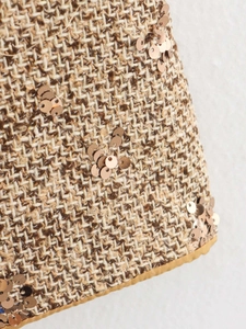 Detailed macro shot of brown and beige tweed fabric with rose gold sequins and satin edging