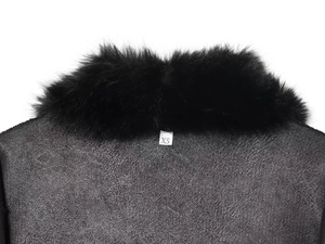 Détail du col en fausse fourrure noire et de l'étiquette XS sur un long manteau en daim