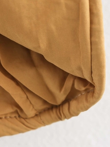 Macro shot of yellow-brown sequin dress fabric with elastic hem and stitching details