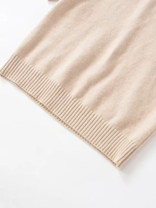 Detail of soft beige knit top showing the elastic ribbed hem and fine fabric texture