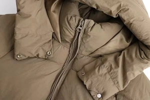 Detail of khaki hooded puffer jacket with metallic zipper and snap button closure