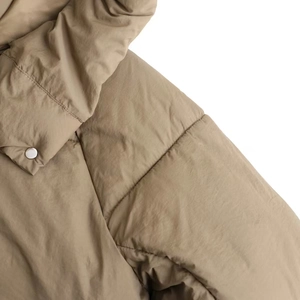 Detailed close-up of khaki quilted jacket featuring horizontal seams and silver metal button