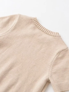 Close-up of ribbed crewneck and fine knit texture on beige short sleeve sweater