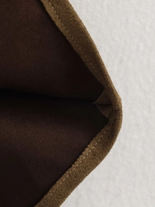 Close-up of brown faux suede fabric showing detailed stitching and inner twill lining
