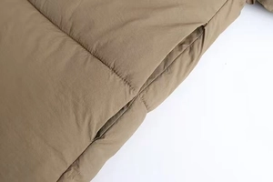 Detail of side pocket on khaki quilted winter jacket with matte windproof fabric texture