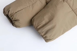 Detail of khaki puffer jacket sleeve featuring elastic windproof cuffs and thick quilting