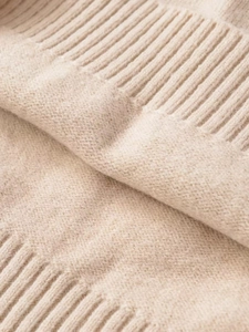 Close-up of oatmeal rib-knit sweater texture showing detailed soft wool fibers
