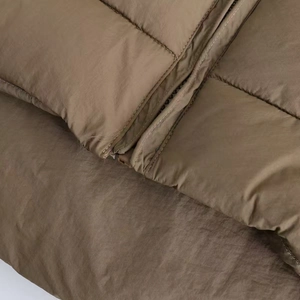 Detail of winter quilted puffer jacket showing matte brown fabric and zipper texture