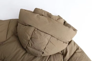 Detailed close-up of a khaki winter puffer coat showing the hooded neck and quilted texture
