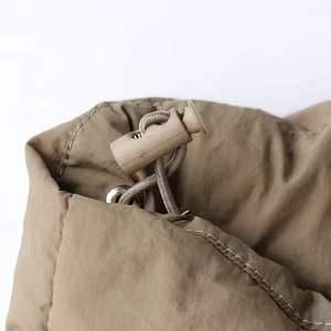 Detailed close-up of adjustable drawstring toggle and cord on khaki winter parka jacket