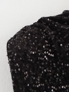 Gros plan sur le tissu à paillettes noires montrant les détails des sequins circulaires