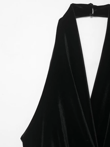 Detail of velvet halter neck dress featuring two back buttons and smooth black fabric texture